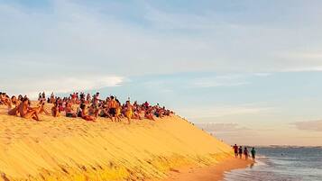 A crowded beach with people sitting and walking along the sand.