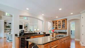 A spacious kitchen with granite countertops, wooden cabinets, and a central island. - 28 Moonshell - Luxury in Folly Field (Hilton Head Island)