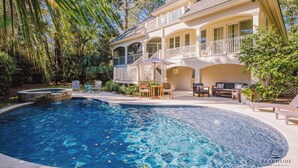 A two-story house with a swimming pool, outdoor furniture, and a covered patio area. - 28 Moonshell - Luxury in Folly Field (Hilton Head Island)