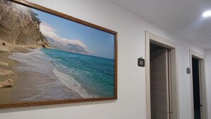 A hallway with a painting of a beach scene, a door labeled "22", and a light switch on the wall. - B&B Fradama' Holiday Dorgali (Dorgali)