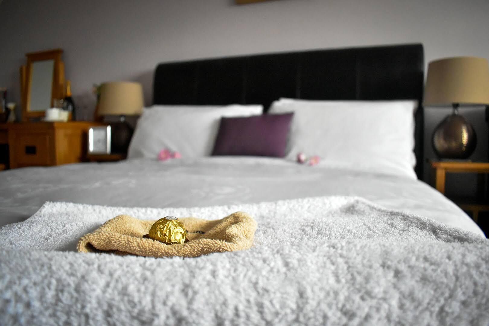 A neatly made bed with a blanket, a pillow, and a wrapped item on the bed.