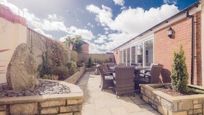 A patio with stone flooring, wicker furniture, and a stone fire feature. - TLC Exmouth Bed and Breakfast (Exmouth)