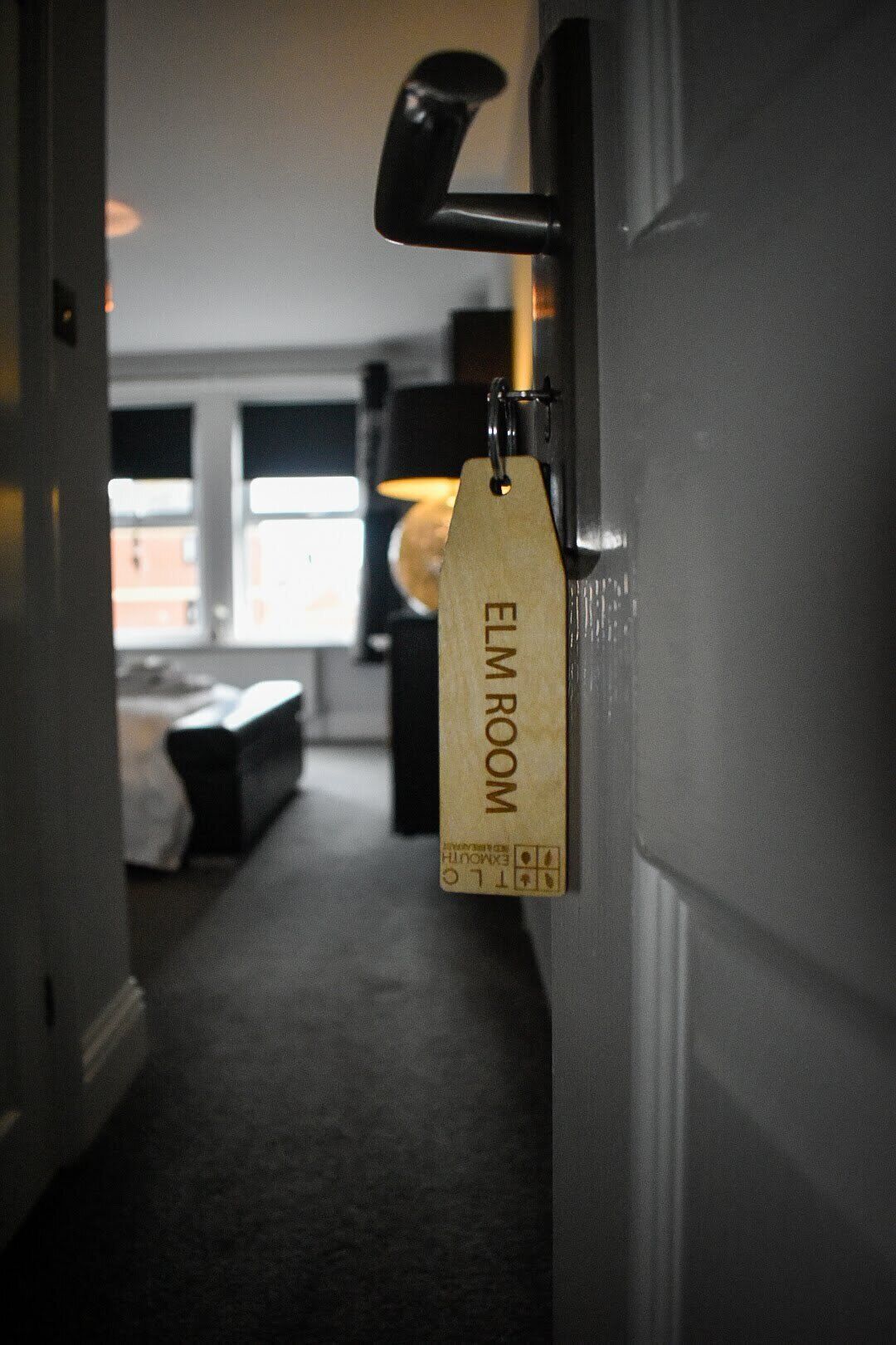 A hallway leading to a room labeled "ELM ROOM" with a door handle and a tag.