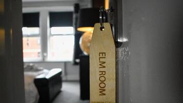 A hallway leading to a room labeled "ELM ROOM" with a door handle and a tag.