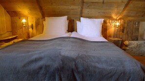 Une chambre confortable dans un chalet en bois, avec un grand lit, deux lampes de chevet et un mur en pierre.