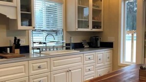 A kitchen with white cabinetry, a wooden countertop, and a large island with a bench.