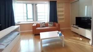 A modern living room with a sofa, a coffee table, a TV, and a window with curtains. - Bs Service Apartment Hotel (Shanghai)