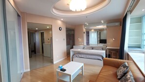 A modern living room with a sofa, a coffee table, and a TV. There is a kitchen area in the background. - Bs Service Apartment Hotel (Shanghai)