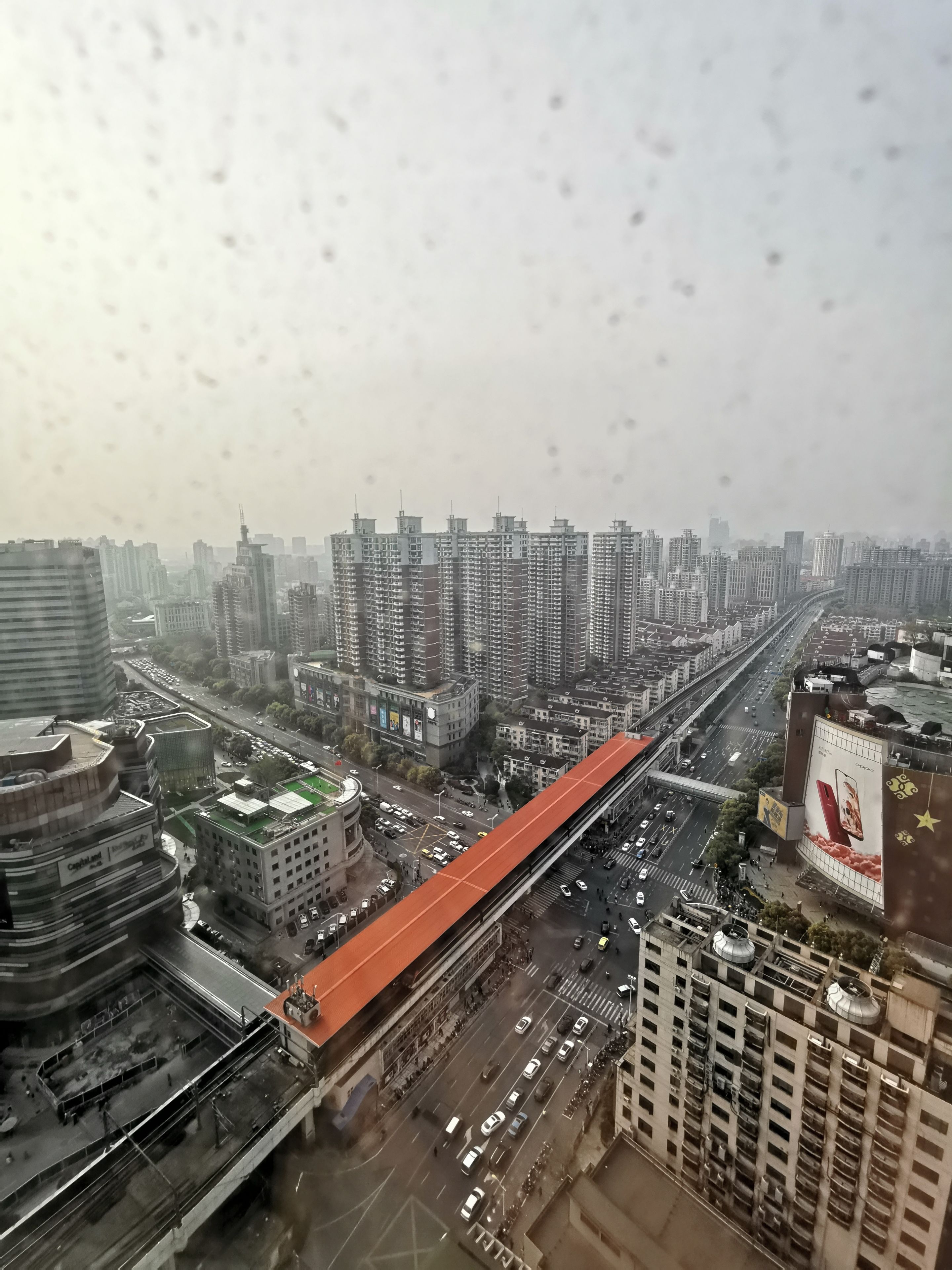 A cityscape with high-rise buildings, a prominent red elevated road, and a busy street with vehicles.