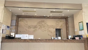 A hotel reception area with a marble counter, a large wall mural, and multiple signs and notices. - Bs Service Apartment Hotel (Shanghai)