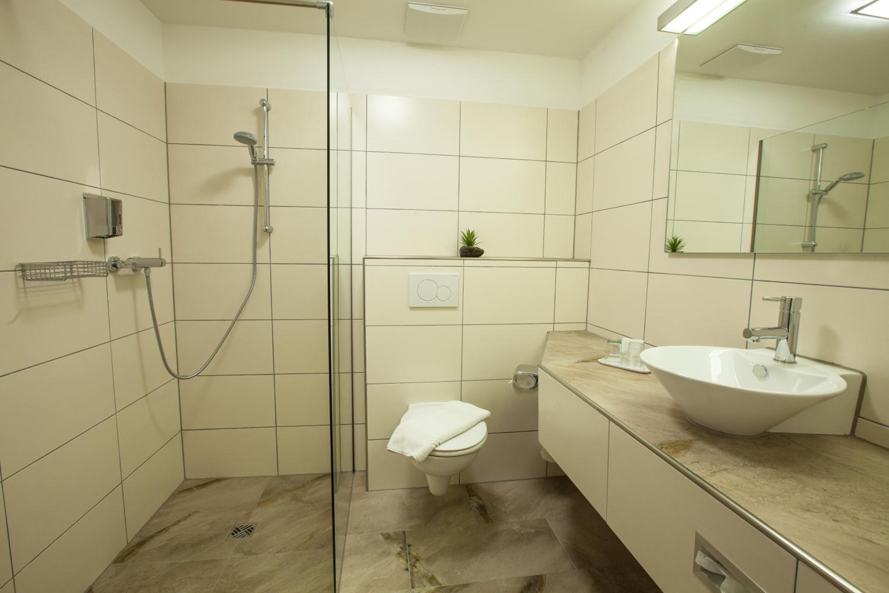 A modern bathroom with a glass-enclosed shower, a white toilet, and a sink with a marble countertop.