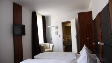A hotel room with a bed, a television mounted on the wall, a chair, and a bathroom visible through an open door.