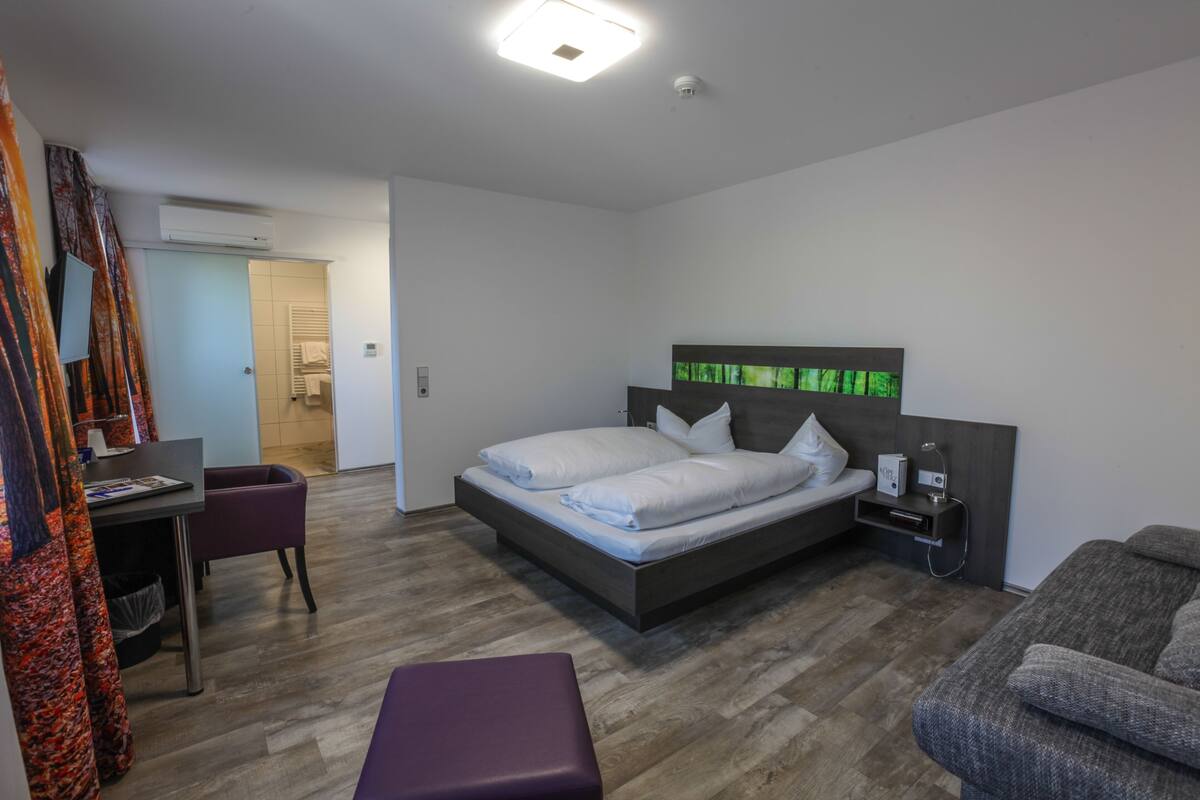 A modern bedroom with a bed, bedside table, and a desk with a chair.