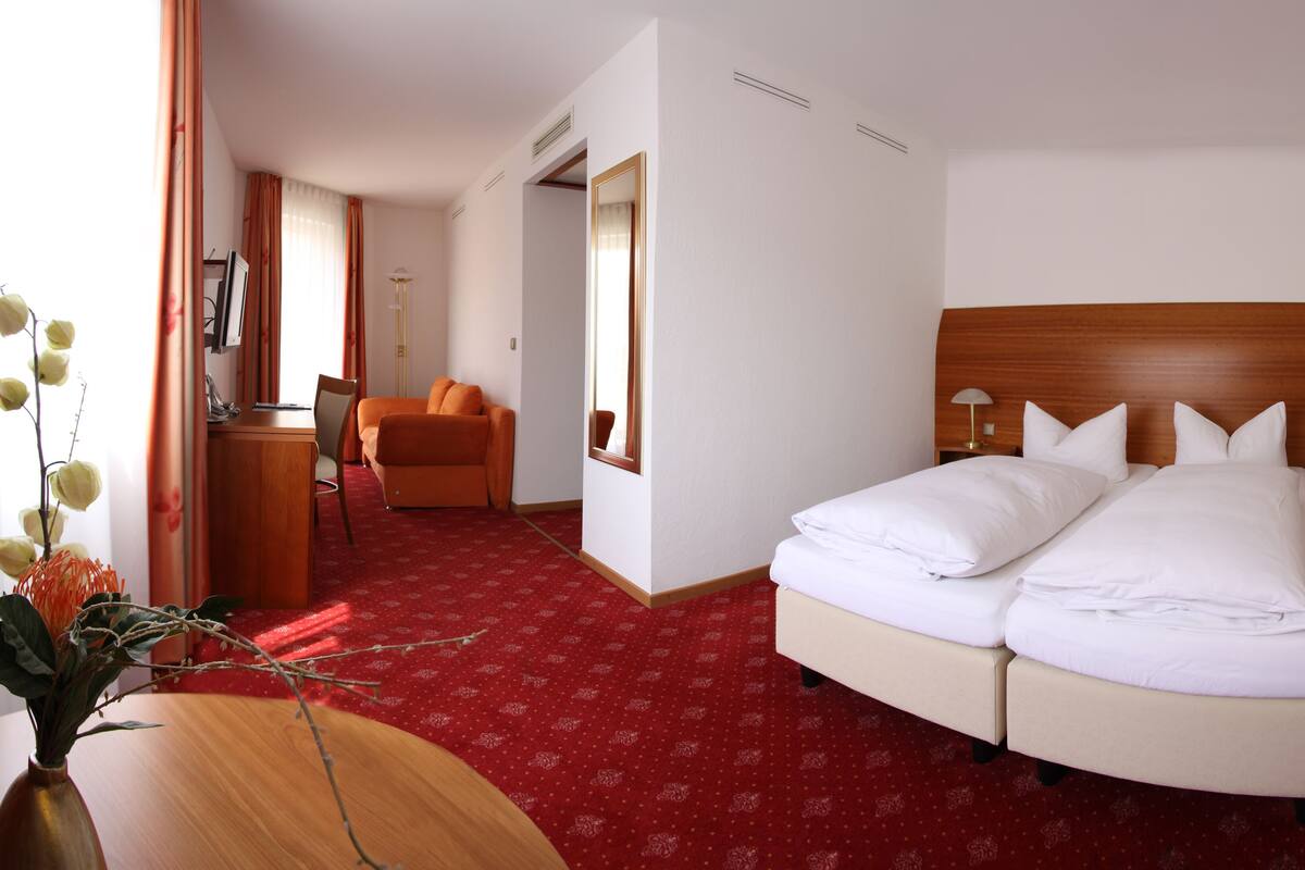 A hotel room with a large bed, two bedside tables, a desk, and a chair.