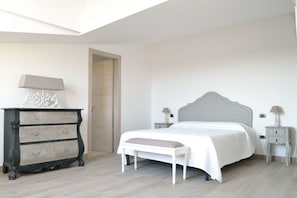 Une chambre à coucher comprenant un lit, des tables de chevet, une commode et un banc.