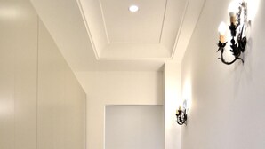 A hallway with a wooden floor, a white table, and a wall-mounted light fixture. - B&B Cloud (Santa Maria Capua Vetere)