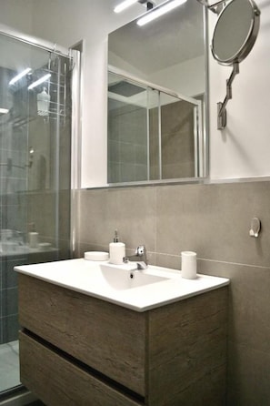 Une salle de bain avec un lavabo blanc, un miroir et un meuble-lavabo en bois.