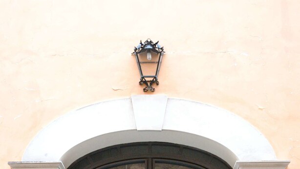 A large, ornate metal gate with a decorative light fixture above it, set within a stone archway. - B&B Cloud (Santa Maria Capua Vetere)