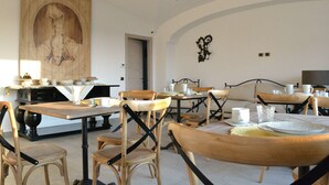 A dining area with wooden tables and chairs, a large wall art piece, and a chandelier. - B&B Cloud (Santa Maria Capua Vetere)