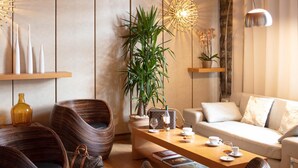 A modern living room with a sofa, two wicker chairs, a wooden coffee table, and a potted plant. - Hotel La Chaumiere (Quillan)