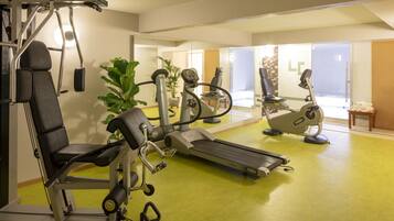 Una palestra con macchinari cardio, pesi e un pavimento verde.