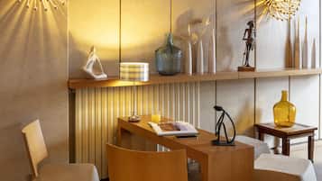 A modern, well-lit room with a wooden desk, two chairs, and a shelf with decorative items.
