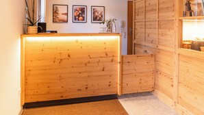 A reception area with a wooden reception desk, framed pictures on the wall, and a wooden panel wall. - Aparthotel Sonnenburg (Schluchsee)