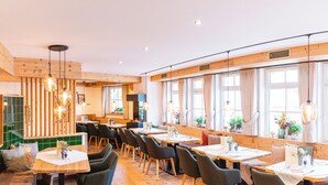 A restaurant with wooden interior, multiple tables, and large windows. - Aparthotel Sonnenburg (Schluchsee)
