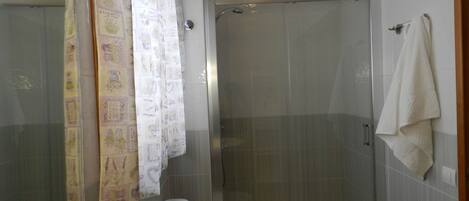 A bathroom with a shower, toilet, and a towel rack.