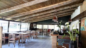 A rustic interior with exposed wooden beams, tiled floors, and a mix of wooden and metal furniture.