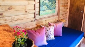 A wooden cabin interior with a blue sofa, wooden walls, and a painting of a landscape.