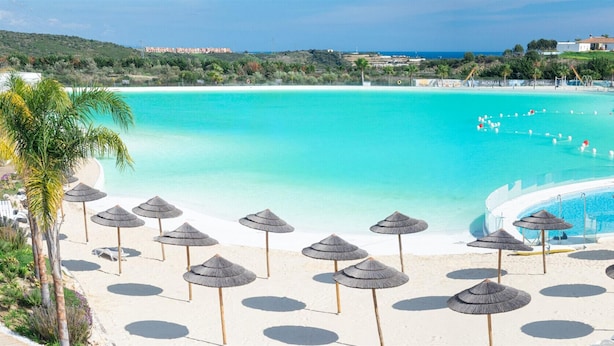 Ein Resort mit einem großen Pool, Strandstühlen und Blick auf den Ozean.