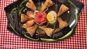 A black plate with fried items and garnishes on a red and white checkered tablecloth. - Villa Bianca (Nainital)