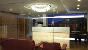 A reception area with a modern design, featuring a reception desk, seating area, and a view of the cityscape through large windows. - Villa Bianca (Nainital)