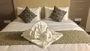 A neatly made bed with a decorative towel, two patterned pillows, and a floral bedspread. - Villa Bianca (Nainital)