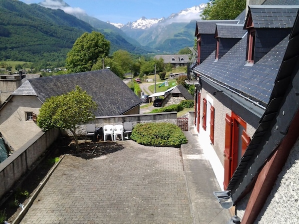 A courtyard with a paved area, a small seating area, and a view of a mountainous landscape.