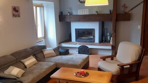 Una sala de estar acogedora con un sofá seccional, una mesa de centro de madera, chimenea y una lámpara colgante.
