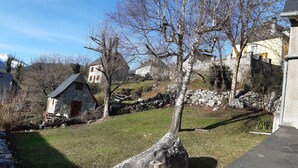 Una casa de piedra con techo inclinado, pared de piedra y un patio cubierto de césped.