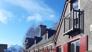 Una casa de dos pisos con un portón rojo y un balcón.