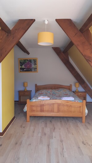 A bedroom with a wooden bed, a hanging lamp, and a nightstand.