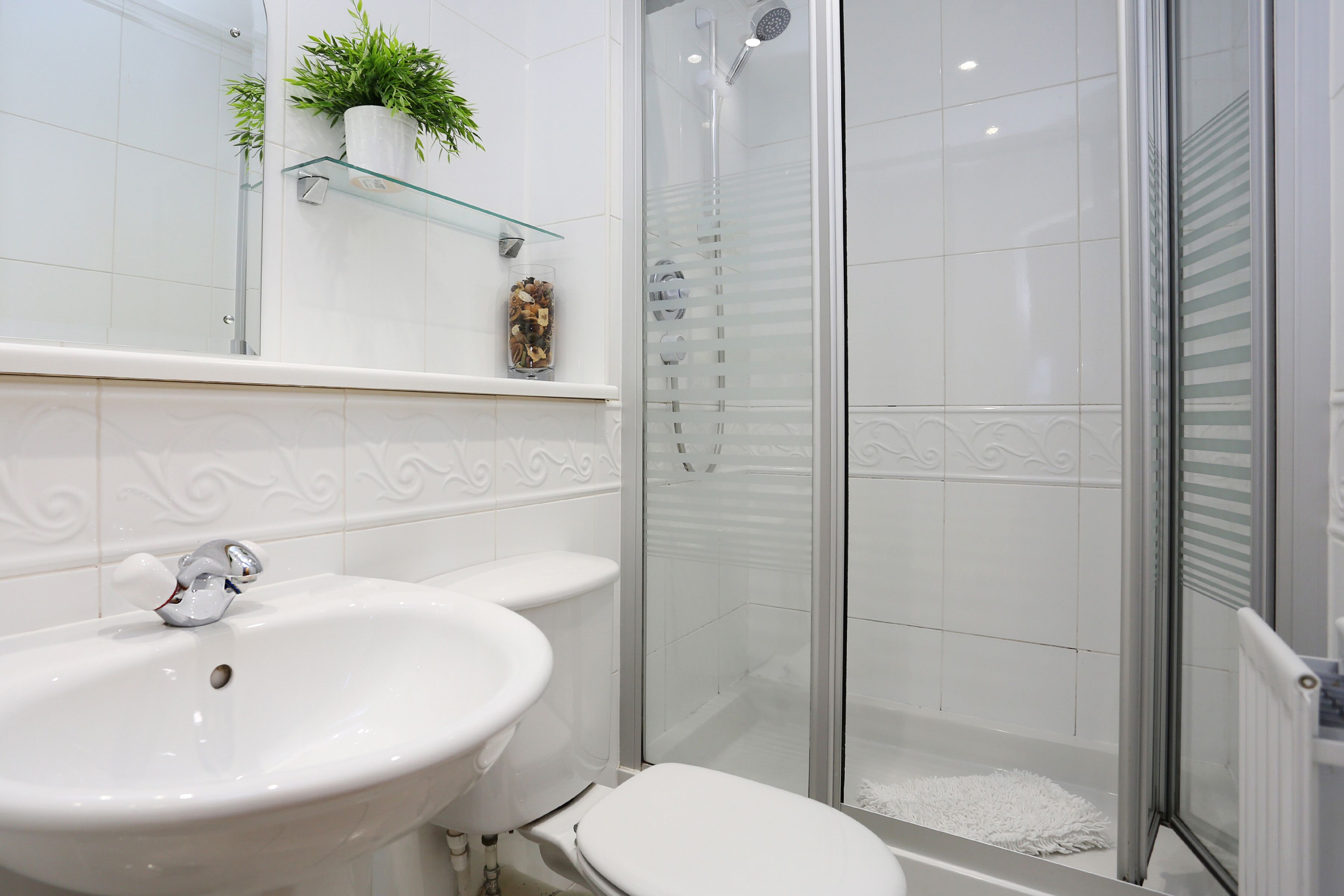 A bathroom with a glass shower enclosure, a white sink, and a toilet.