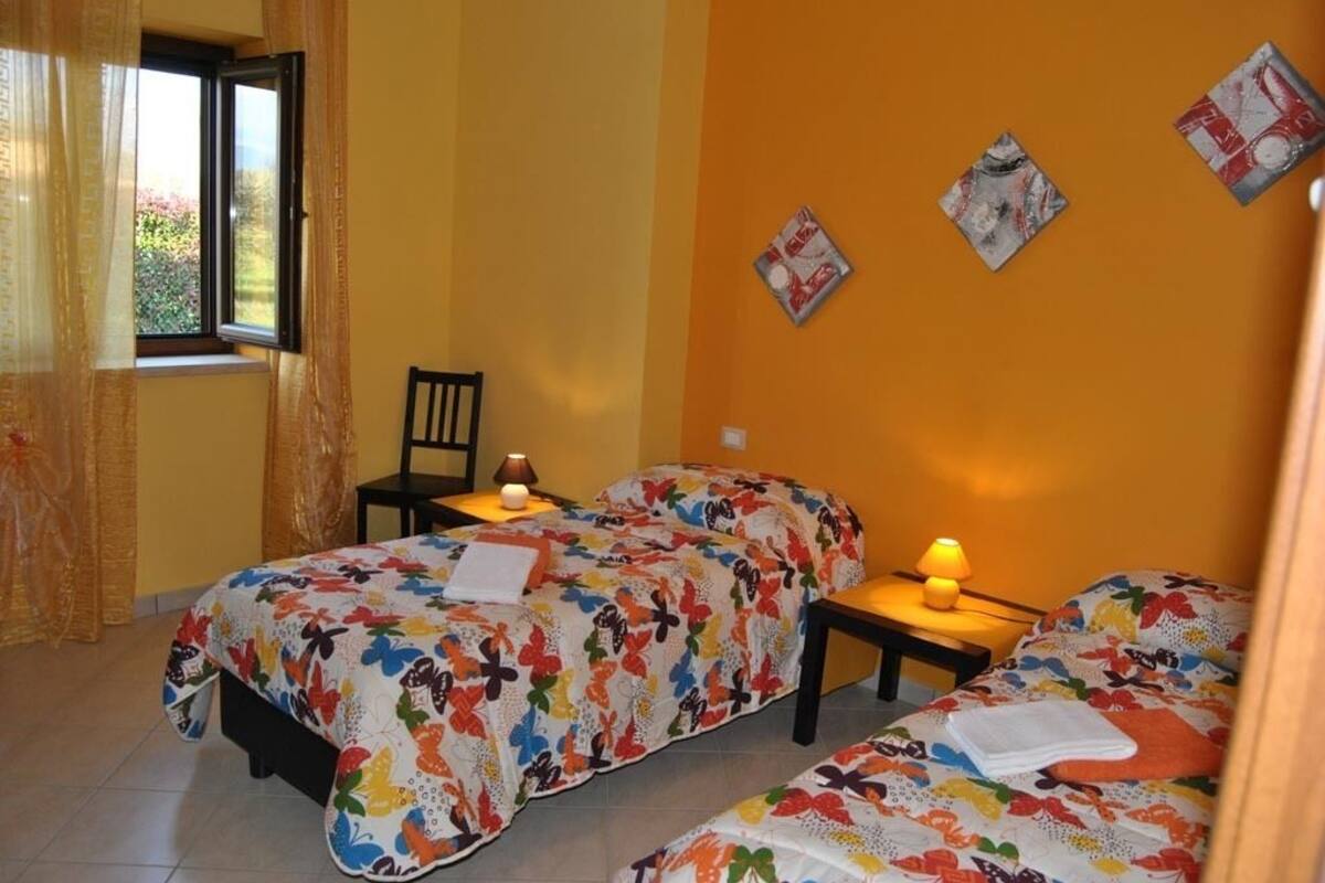 Un dormitorio con dos camas, una silla y dos mesitas de noche con lámparas.