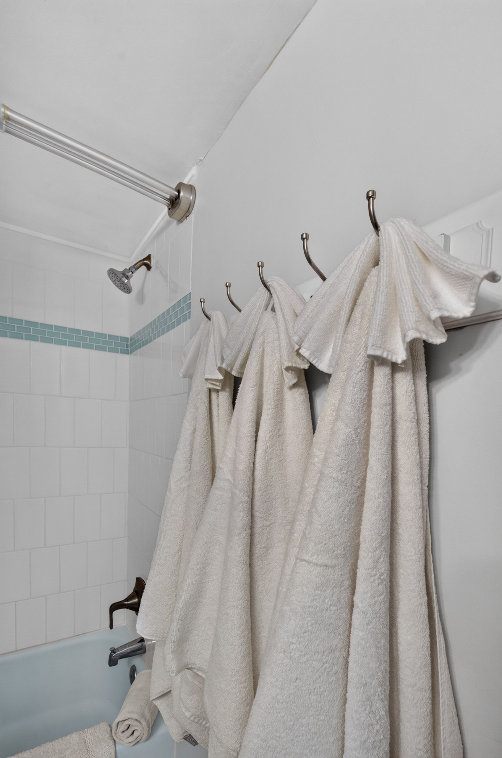 Une salle de bain avec une douche, un porte-serviettes avec plusieurs serviettes et une baignoire.