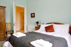A bedroom with a bed, a chair, a wardrobe, and a door leading to another room. - Luxury Central Old Town Suite Edinburgh (Edinburgh)