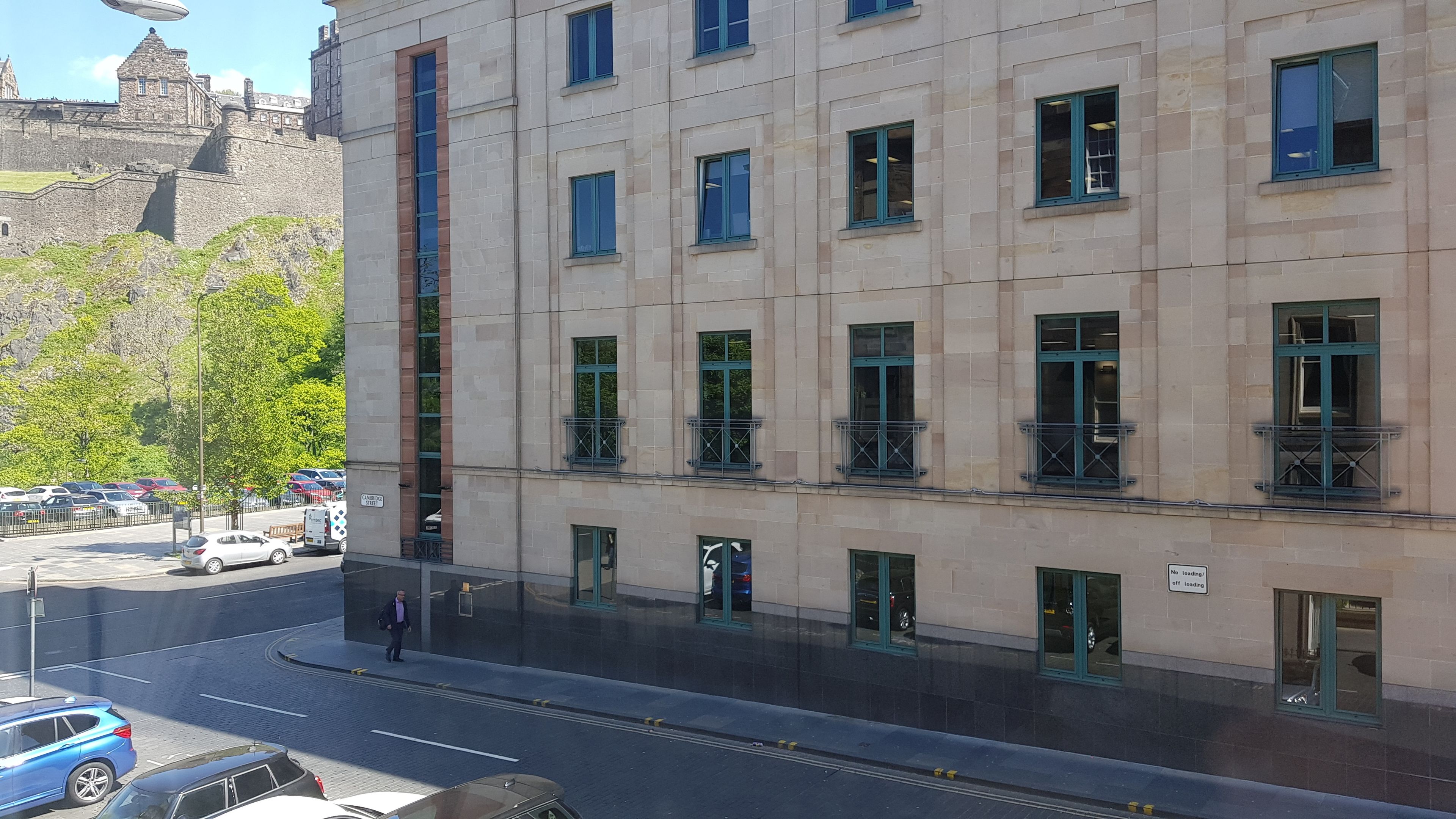 Ein mehrstöckiges Gebäude mit einer Stein-Fassade, zahlreichen Fenstern und einem sichtbaren Eingang.