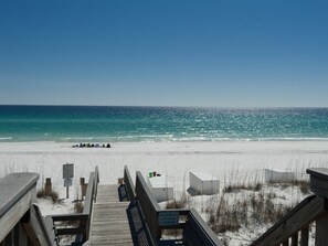 A wooden boardwalk leading to a beach with a clear view of the ocean.