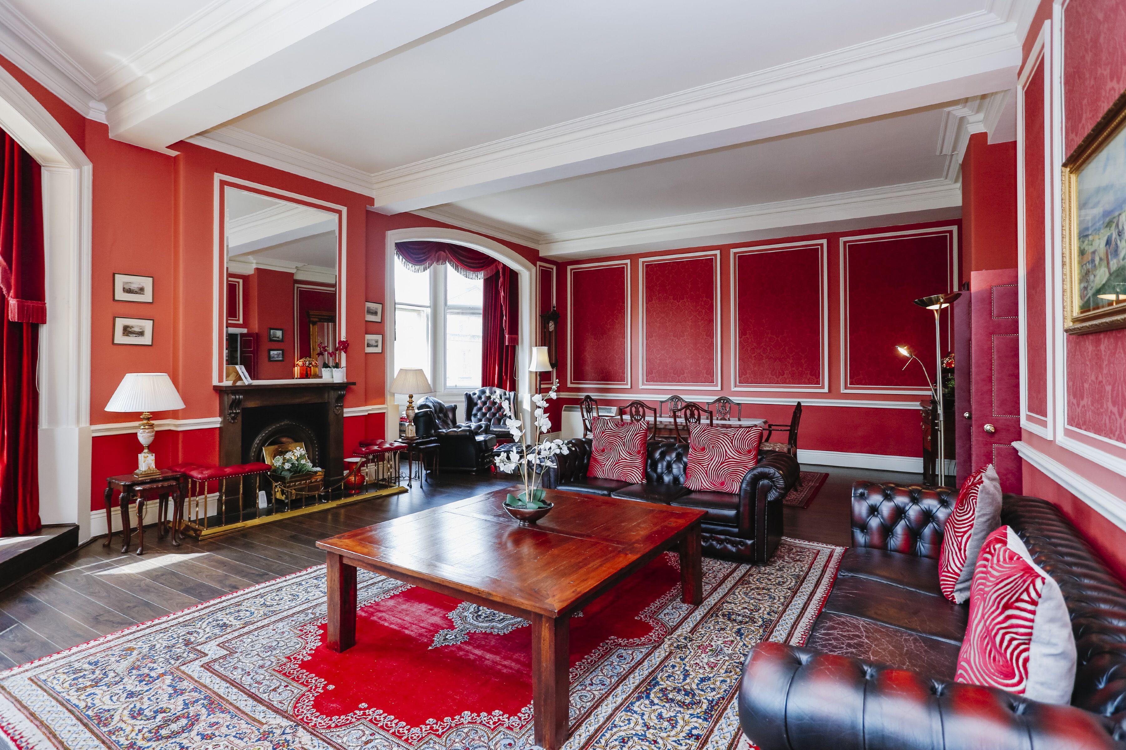 A traditional living room with a fireplace, red walls, and classic furniture.