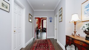 A hallway with a patterned rug, a wooden desk with a lamp, and a door leading to another room. - Gorgeous Royal Mile Mansion Apartment (Edinburgh)