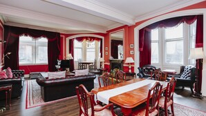 A traditional living room with a fireplace, red curtains, and a dining area with wooden furniture. - Gorgeous Royal Mile Mansion Apartment (Edinburgh)