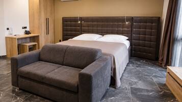 A hotel room with a bed, a sofa, a wooden cabinet, and a marble floor.